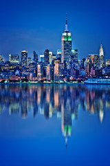 Photo of New York City skyline, Empire State building illuminated with water reflections at night during blue hour