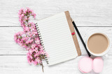 Creative layout made with spring cherry blossoming flowers, blank notepad, macaroons and coffee cup