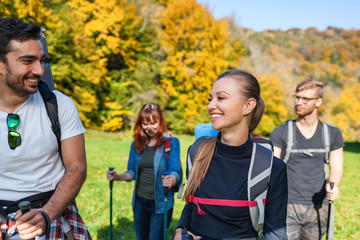 Wall Mural - group of smiling friends trekking together in the nature, hikers exploring places