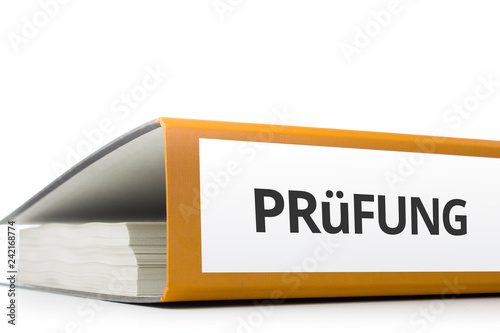 Fotografía oranger Aktenordner gefüllt mit Papierseiten und Beschriftung Prüfung liegend vo