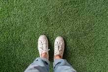 Top View Of Female Feet With Sneakers Standing On  Green Artificial Grass