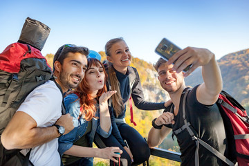 Friends with backpacks making selfie photo together at the peak of mount, travel and tourism concept