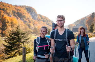 Wall Mural - authentic group of friends on tourist trip walking with backpacks and trekking sticks