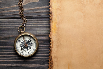 Vintage compass and blank paper sheet on wooden table