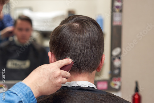 Guy Looking Into A Mirror While Getting Haircut In Barbershop