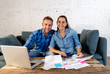 © SB Arts Media - Young happy young couple paying bills with laptop feeling fortunate and lucky off debts