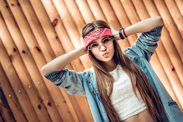 Wall Mural - Modern young woman in red bandage and round sunglasses posing at camera.Lifestyle,trendy concept.