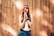 Beautiful Girl In Bright Red Bandana Holding Candy Lollipop. Young Cheerful Woman Hiding Out Eye With Lollipop At Background, Copy Space.