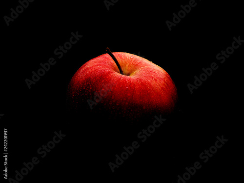 Cuadros en Lienzo Red ripe apple with water drops. The apple disappears on a black