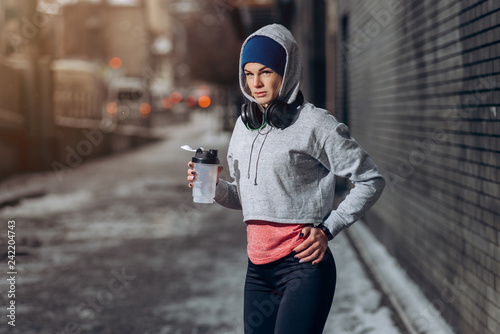 Fotografia Fit woman drinking protein shake on winter day in city