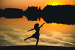 © volhavasilevich - Silhouette of a young beautiful girl in a jump on a background of a sunset in reflection pond