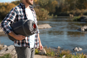 Wall Mural - Male camper with sleeping bag near pond. Space for text