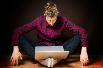 young man sit on floor and use laptop on dark background b