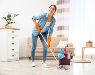 Wall Mural - Young woman washing floor with mop in living room. Cleaning service