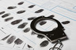 Police handcuff and criminal fingerprints card, closeup