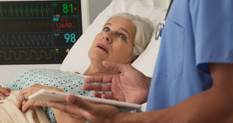 sick elderly woman lying in hospital bed after surgery talking to nurse. positive senior patient rec