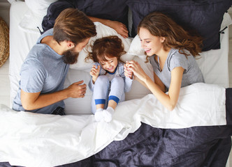 Wall Mural - happy family mother, father and child  in bed.