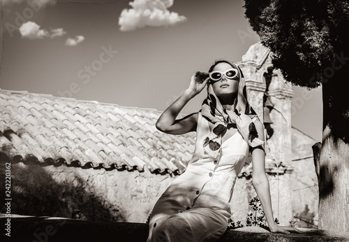 Young girl dressing in 60s style clothes in a village with old church on background Tableau sur Toile