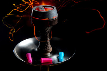 Shisha bowl with craft tobacco and red coil with hookah smoke background.