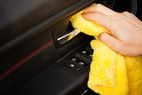 Fototapeta Przestrzenne - Clining car. Wiping panel of a luxury car with yellow microfiber, close-up view