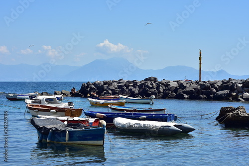 Fotografía Small recreational and fishing boats moored in calm water behind artificial breakwall made of free laid stones on Mediterranean coast