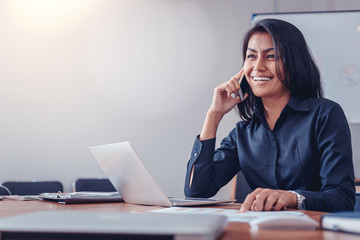 businesswoman in black shirt talking by mobile phone in office