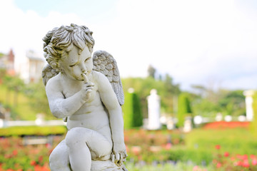 Cupid sculpture in summer garden outdoor.