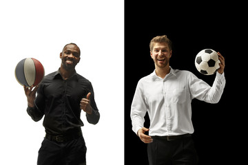 Wall Mural - Portrait of a smiling men holding soccer and basketball ball isolated on a white and black background. The success happy afro and caucasian men. Mixed couple.