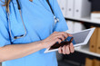Woman doctor using tablet computer while standing straight in hospital office, closeup. Healthcare, insurance and medicine concept