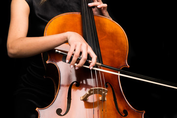 Wall Mural - Young girl playing the cello on isolated black background