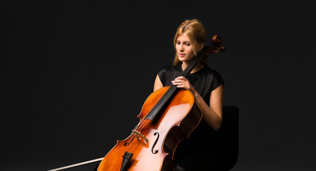 Wall Mural - Young girl playing the cello on isolated black background