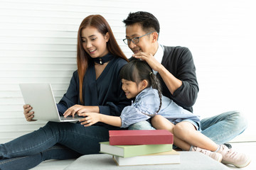 Sticker - Family Asian mother and father with daughter happy together in livingroom at home. they play computer.