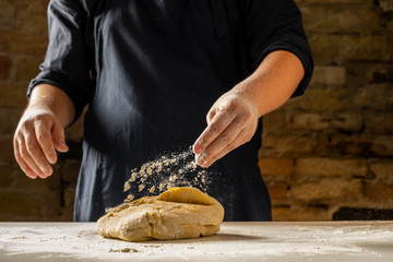 Wall Mural - Close view of baker hands kneading dough for traditional bread. Food recipe concept.