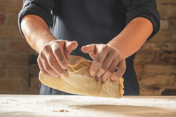 Wall Mural - Close view of baker hands kneading dough for traditional bread. Food recipe concept.