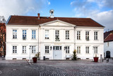 Fototapeta  - Germany, Prignitz, Pritzwalk: Panorama front view of town hall in the city center of the small German town with main entrance, public square and blue sky - concept administration.