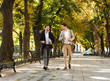 © Drobot Dean - Photo of young businessmen in suits walking outdoor through green park with takeaway coffee and laptop, during sunny day