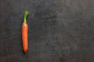 Bright ripe carrots with leaves on the table. Concept-healthy food, vegetarianism, raw food, a source of carotene and vitamins A,B .