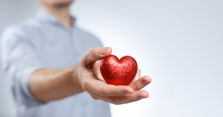 Wall Mural - Man holding a red small heart on grey background