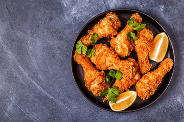 Wall Mural - Fried chicken legs with lemon and parsley.