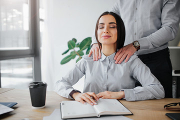 young woman get attention from boss. he does shoulder massage for her. she is relaxed and pleased. y