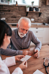 Nurse or doctor talking to a senior patient about medication at home.