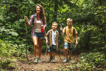 Wall Mural - mother and her little sons hiking trough forest.spring concept.