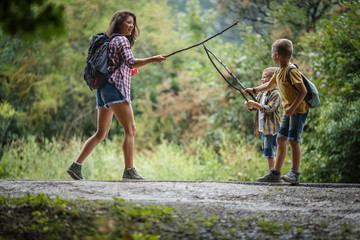 Wall Mural - mother and her little sons hiking trough forest. having fun with wooden sticks.