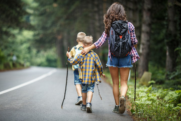 Wall Mural - mother and her little sons hiking by the rural country road.outdoor spring leisure concept.