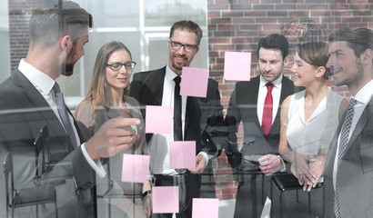 group of business people looking at notes on glass