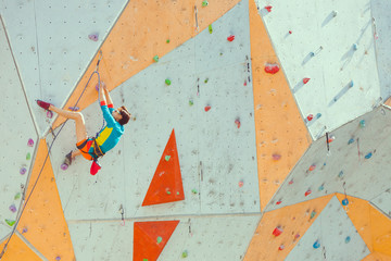 Wall Mural - A girl climbs a climbing wall.