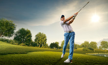 Male Golf Player On Professional Golf Course. Golfer With Golf Club Taking A Shot
