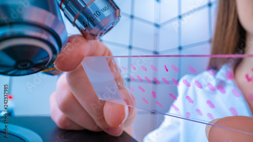 Fotomural Young woman technician is examining a histological sample, a biopsy in the labor