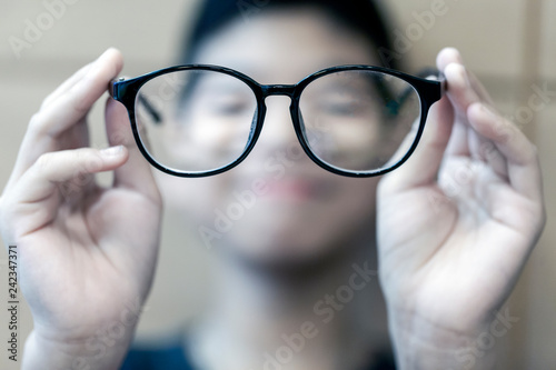 Cuadros en Lienzo The Black frame glasses on the hands of boys with short-sighted eyes in front