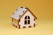 © Mykola - Wooden toy house model on yellow background side view